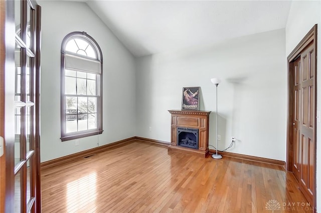 unfurnished living room featuring lofted ceiling and light hardwood / wood-style flooring