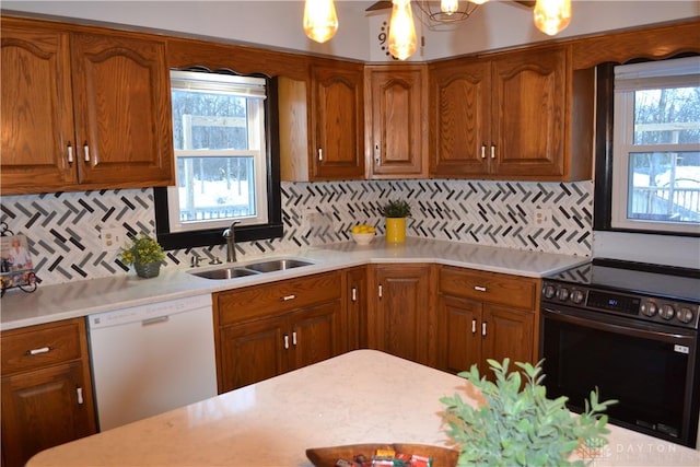 kitchen with hanging light fixtures, electric range, backsplash, white dishwasher, and sink