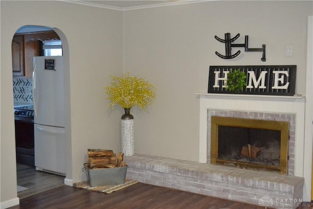 4403 Clayton Rd, Perry Twp, OH 45309 - unfurnished living room featuring arched walkways, wood finished floors, crown molding, and a brick fireplace