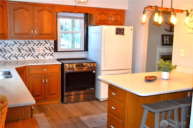 4403 Clayton Rd, Perry Twp, OH 45309 - kitchen with electric stove, freestanding refrigerator, light wood-style floors, light countertops, and brown cabinetry