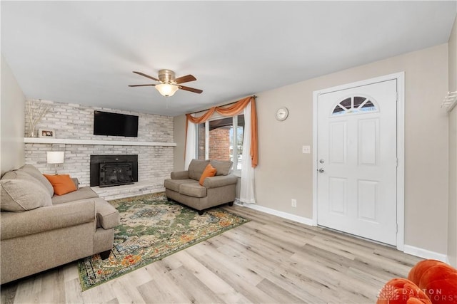 living room featuring a brick fireplace, light wood-type flooring, and ceiling fan