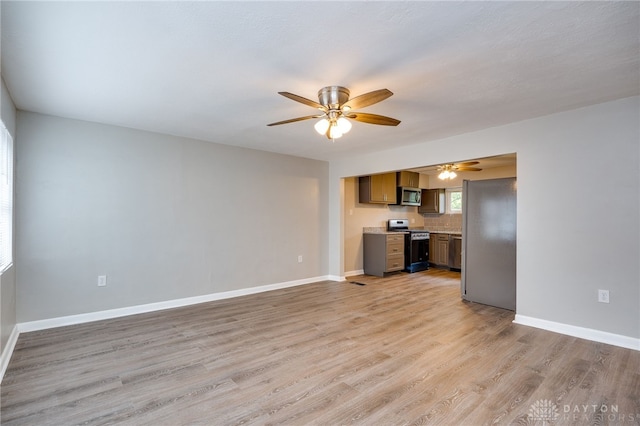 unfurnished living room featuring baseboards, a ceiling fan, and light wood finished floors