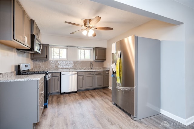 kitchen featuring ceiling fan, decorative backsplash, gray cabinets, appliances with stainless steel finishes, and light wood-style floors