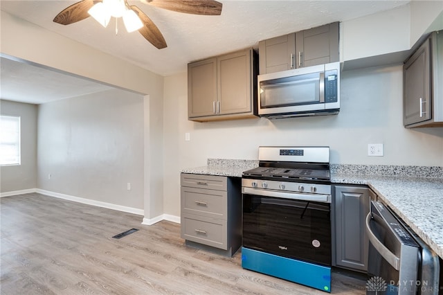 kitchen featuring light wood-style flooring, gray cabinetry, stainless steel appliances, and a ceiling fan