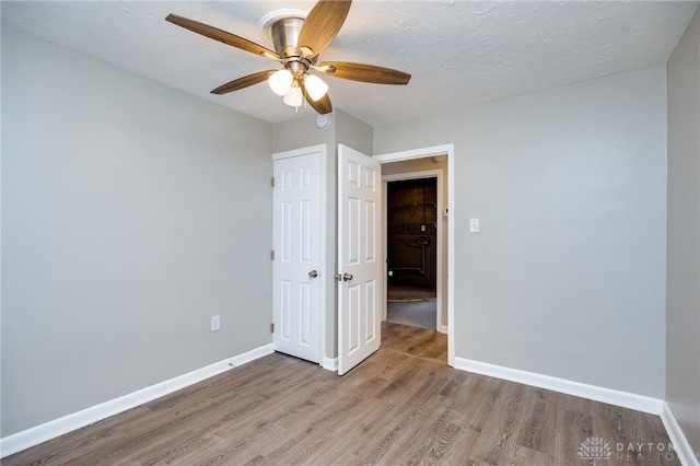 unfurnished bedroom with wood finished floors, baseboards, and a textured ceiling