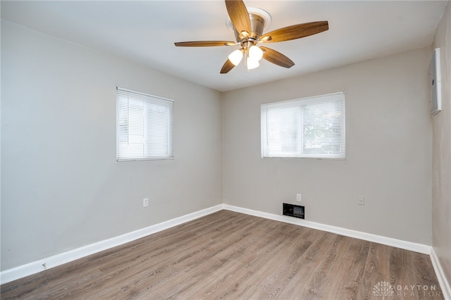 empty room featuring visible vents, a ceiling fan, baseboards, and wood finished floors