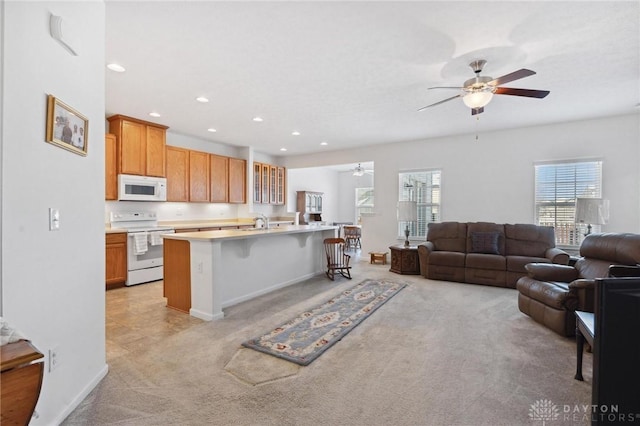 kitchen featuring white appliances, an island with sink, a breakfast bar, light carpet, and sink