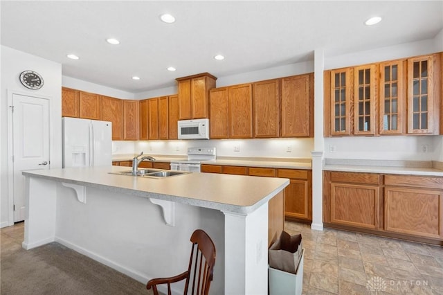 kitchen with sink, white appliances, a kitchen breakfast bar, light carpet, and a center island with sink