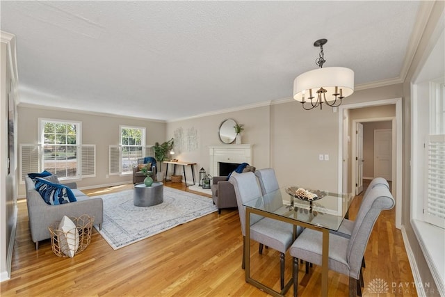 dining room with a notable chandelier, light hardwood / wood-style flooring, crown molding, and a textured ceiling