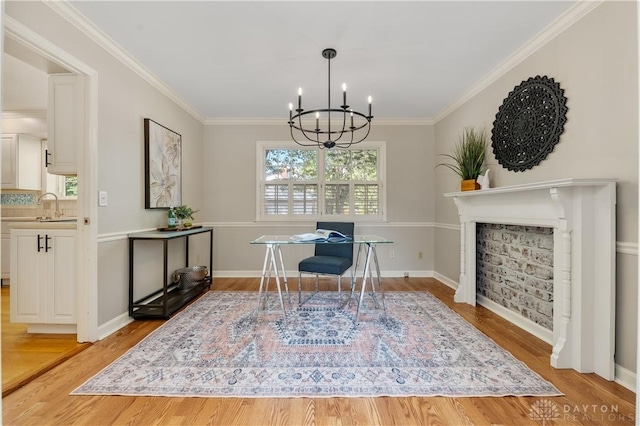 dining area with ornamental molding, light hardwood / wood-style floors, a chandelier, and sink