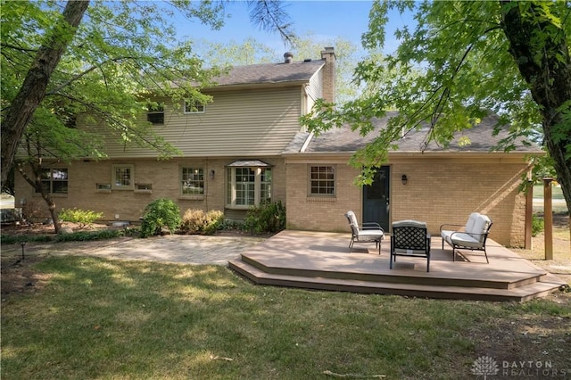 rear view of property with an outdoor fire pit, a lawn, and a wooden deck