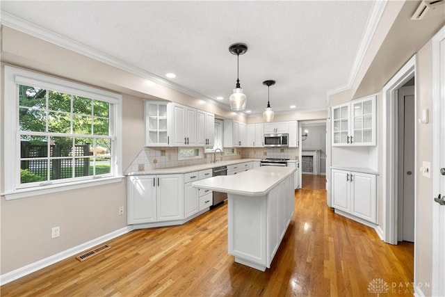 kitchen with stainless steel appliances, white cabinets, a center island, and backsplash