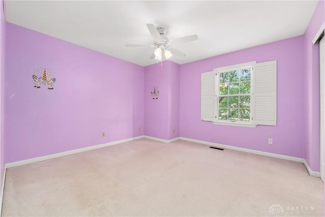 empty room featuring ceiling fan and light carpet