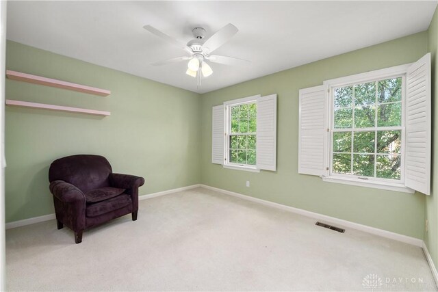 sitting room featuring ceiling fan, light carpet, and a healthy amount of sunlight