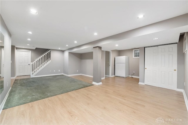 basement featuring light hardwood / wood-style floors and white fridge