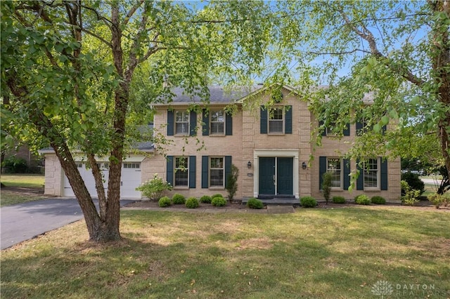 colonial home with a front lawn and a garage