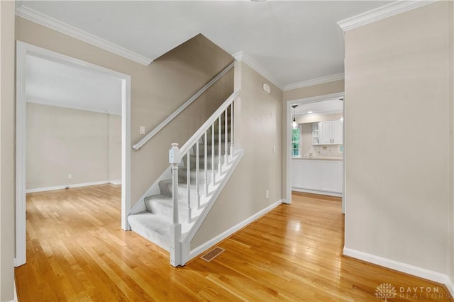 staircase with ornamental molding and hardwood / wood-style floors