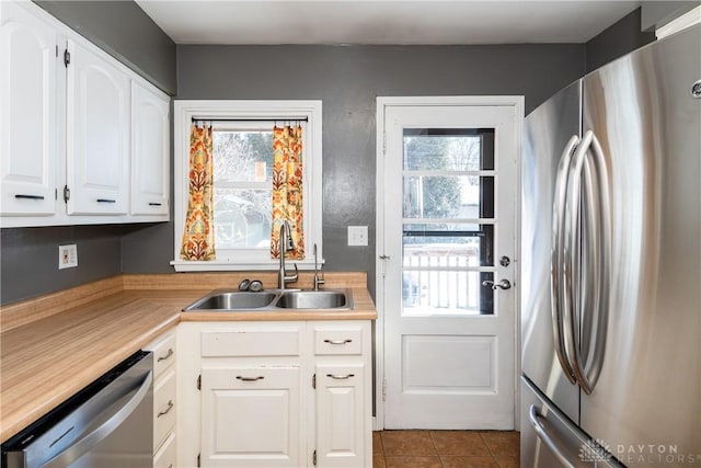 kitchen with stainless steel appliances, white cabinets, sink, and light tile patterned floors