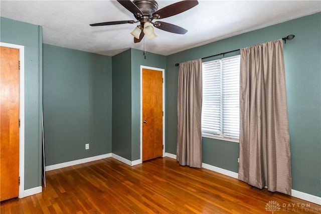 unfurnished bedroom featuring multiple windows, ceiling fan, and dark wood-type flooring