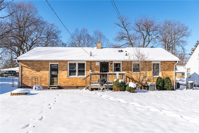 snow covered back of property with a wooden deck