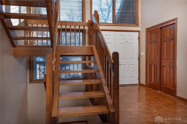 stairway with a towering ceiling and parquet floors