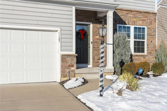 snow covered property entrance with a garage