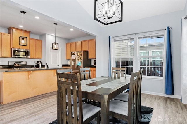 dining room featuring vaulted ceiling, light hardwood / wood-style floors, and a notable chandelier