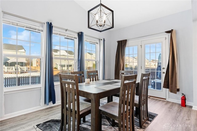 dining room with hardwood / wood-style floors, lofted ceiling, a chandelier, and plenty of natural light