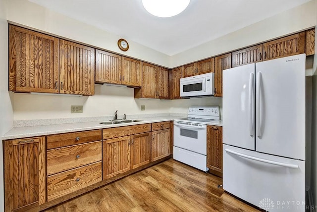 kitchen featuring white appliances, light wood-type flooring, and sink