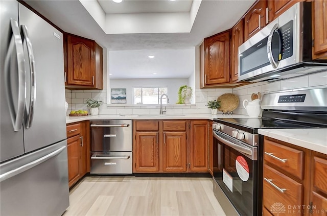 kitchen with appliances with stainless steel finishes, tasteful backsplash, a raised ceiling, and sink