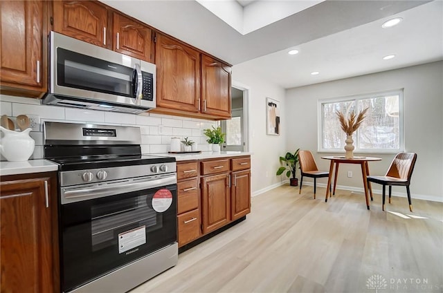 kitchen featuring stainless steel appliances, light wood-type flooring, and decorative backsplash