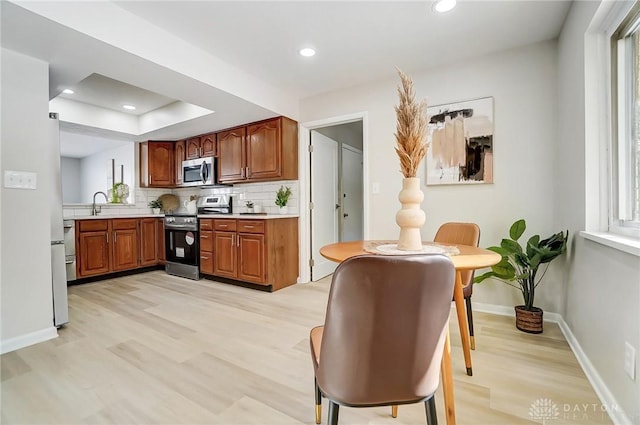 kitchen featuring light hardwood / wood-style floors, stainless steel appliances, backsplash, and sink