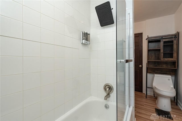 bathroom featuring hardwood / wood-style flooring, toilet, and tiled shower / bath combo