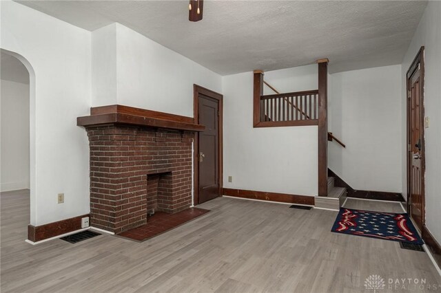 unfurnished living room featuring a fireplace, a textured ceiling, and hardwood / wood-style floors