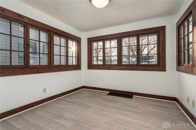 unfurnished room featuring light wood-type flooring and a textured ceiling