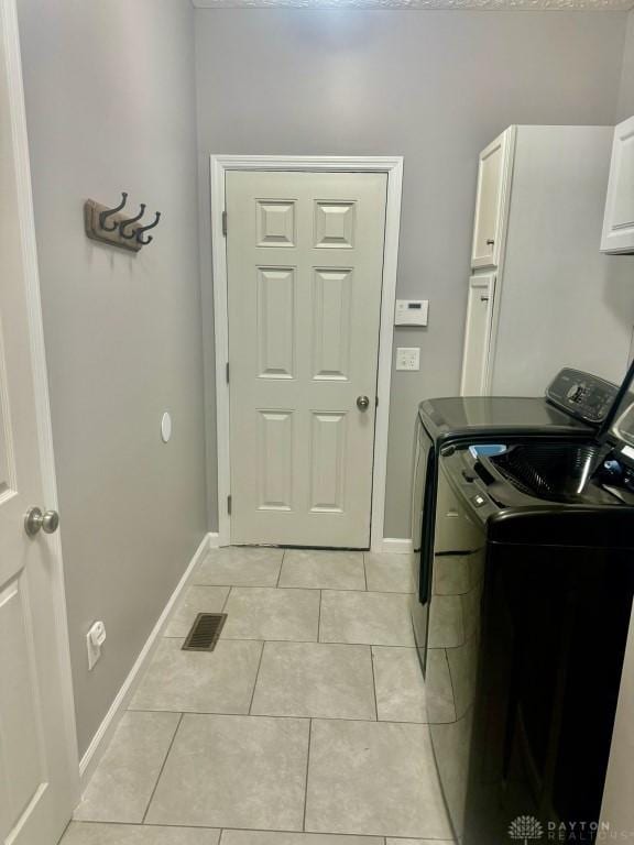 laundry area with light tile patterned flooring, cabinets, and independent washer and dryer