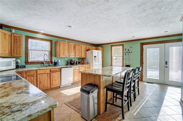 kitchen featuring sink, a center island, french doors, white appliances, and light tile patterned floors