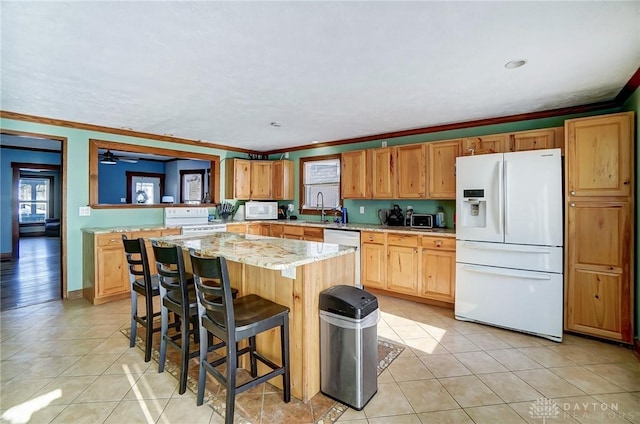 kitchen with white appliances, a kitchen breakfast bar, ornamental molding, and a kitchen island