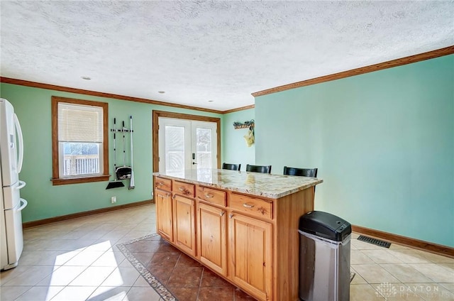 kitchen featuring white refrigerator, a textured ceiling, light tile patterned floors, and crown molding