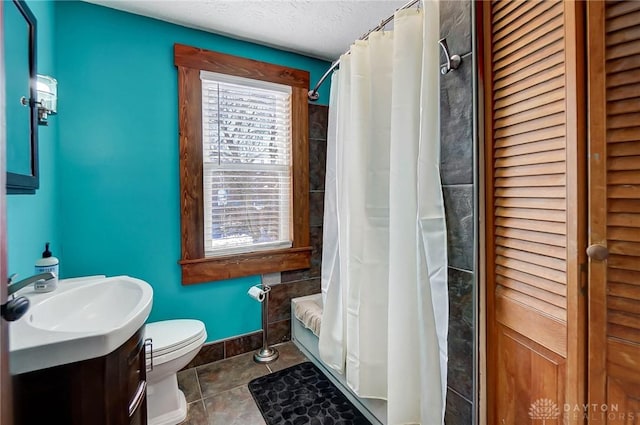 bathroom with a textured ceiling, tile patterned floors, vanity, and toilet