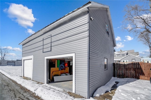 view of snow covered exterior with a garage and an outbuilding