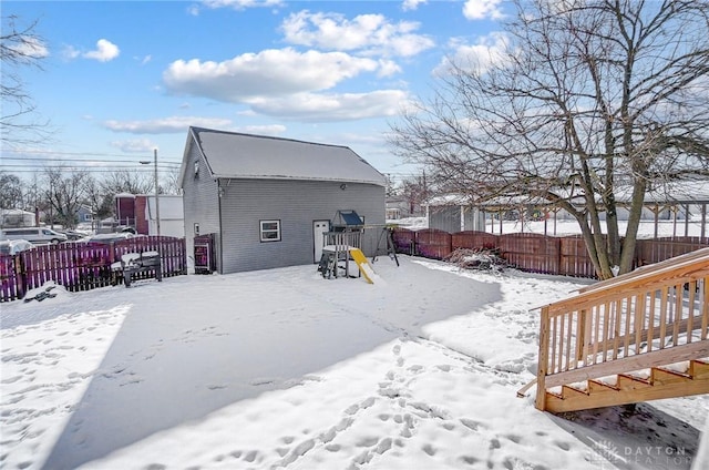 snow covered back of property featuring a playground