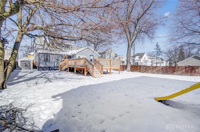 snowy yard featuring a deck and a shed