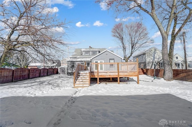 snow covered back of property with a deck