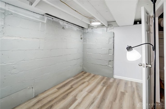 basement with brick wall and wood-type flooring