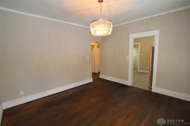 spare room with arched walkways, dark wood-style flooring, baseboards, and crown molding