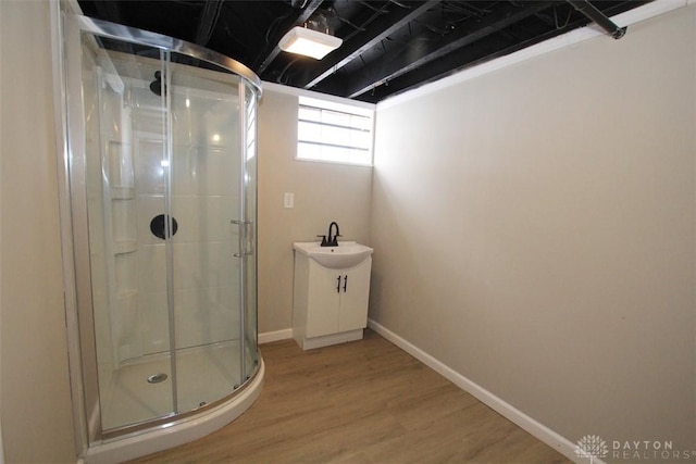 full bath with a stall shower, baseboards, and wood finished floors