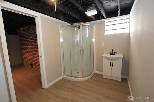 bathroom featuring a stall shower, baseboards, brick wall, and wood finished floors