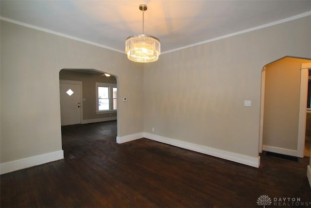 empty room with ornamental molding, arched walkways, dark wood finished floors, and baseboards