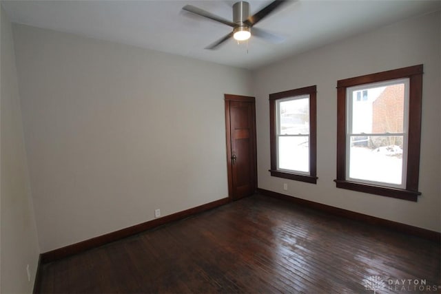 unfurnished room featuring dark wood-style floors, ceiling fan, and baseboards